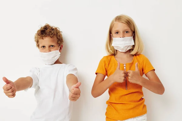 Muchacho y niña divertido médico máscara de pie lado a lado primer plano luz fondo — Foto de Stock