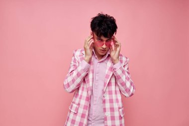 Genç bir adamın portresi pembe gözlüklü kareli ceket modası pembe arka plan değiştirilmemiş.