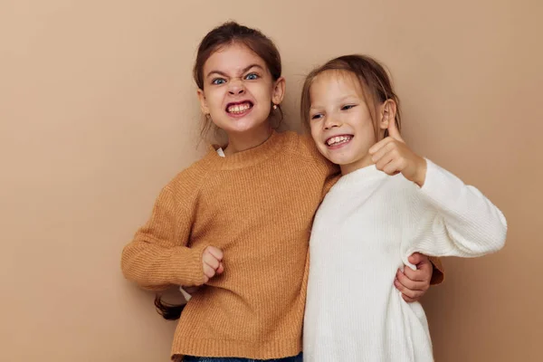 Duas engraçadas meninas abraço amizade posando fundo bege — Fotografia de Stock