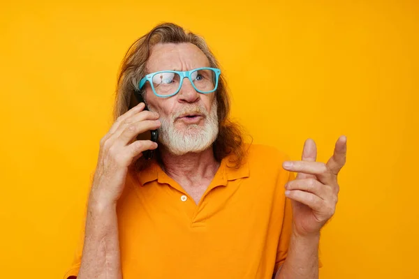 Vieil homme portant des lunettes bleues chemise jaune parlant sur le téléphone vue recadrée — Photo
