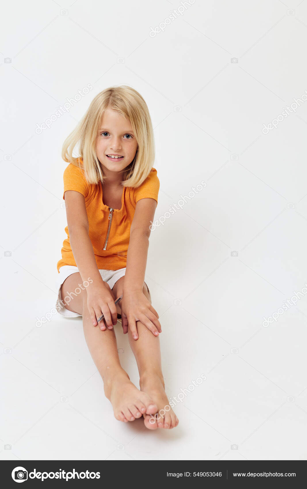 Una niña alegre con una camiseta amarilla se sienta en el suelo con las  piernas dobladas: fotografía de stock © Kulyashina #549053046