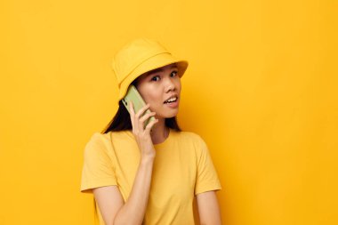 Elinde telefon tutan kadın yaşam teknolojisi pozu veriyor sarı arka plan değiştirilmemiş