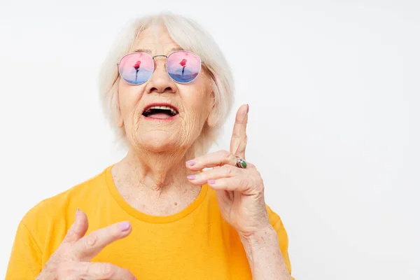 Portrait of an old friendly woman in fashionable glasses hand gestures isolated background — Stock Photo, Image