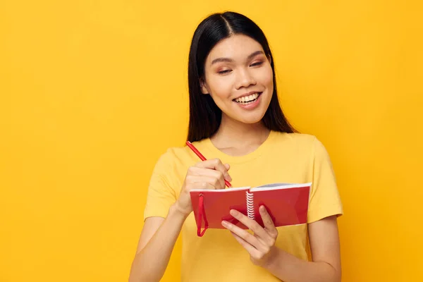 Charmante jeune femme asiatique dans un t-shirt jaune carnet rouge formation fond jaune inchangé — Photo