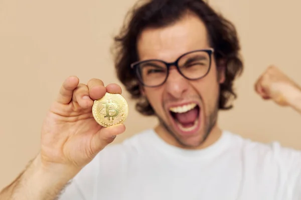 Hombre en una camiseta blanca con Bitcoin criptomoneda fondo beige — Foto de Stock