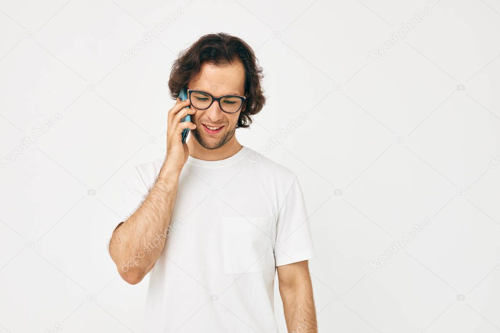 Attractive man in a white T-shirt communication by phone isolated background