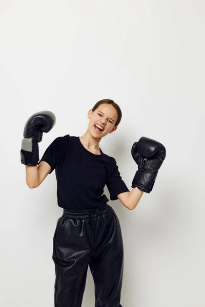 Joven mujer en negro deportes uniforme guantes de boxeo posando fondo aislado — Foto de Stock