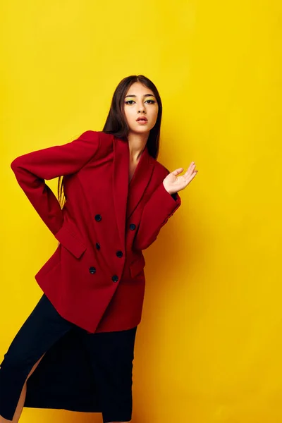 Attraktiv flicka i en röd jacka kosmetika leende gul bakgrund oförändrad — Stockfoto