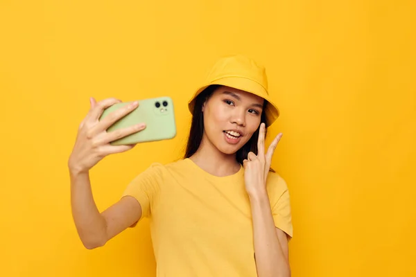 Γυναίκα με ασιατική εμφάνιση κρατώντας ένα τηλέφωνο θέτοντας τεχνολογία lifestyle απομονωμένη φόντο αμετάβλητη — Φωτογραφία Αρχείου