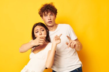 Beyaz tişörtlerle yan yana duran sevimli genç çift yaşam tarzını değiştirmeden poz veriyor.