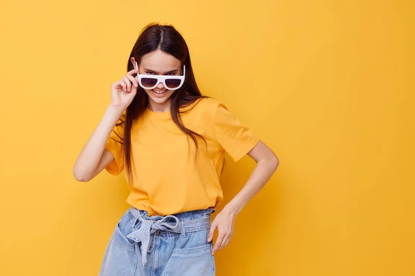 Menina bonita com cabelos longos usando óculos de sol posando fundo amarelo — Fotografia de Stock