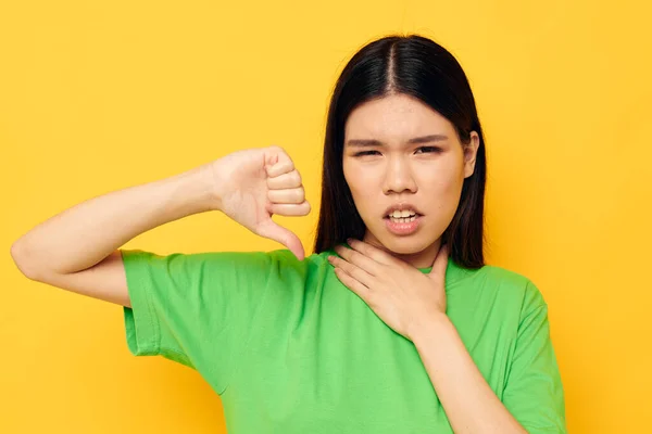 Encantadora joven mujer asiática en verde camisetas gestos con sus manos emociones modelo de estudio inalterado — Foto de Stock