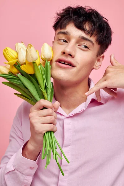 Фото романтичного молодого хлопця в рожевій сорочці з букетом квітів жестом своїми руками Стиль життя незмінний — стокове фото