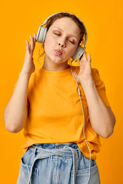 Komik kız sarı t-shirt kulaklıklar eğlenceli müzik izole edilmiş arka planlar değiştirilmemiş — Stok fotoğraf