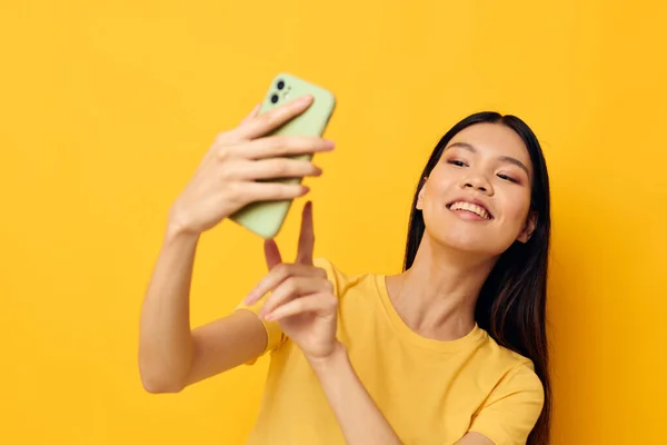 Donna con aspetto asiatico con un telefono tra le mani fa un modello di studio selfie inalterato — Foto Stock