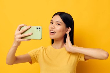 Asyalı görünümlü, akıllı telefonlu bir kadın. Eğlenceli duygular, yakın çekim stüdyo modeli.