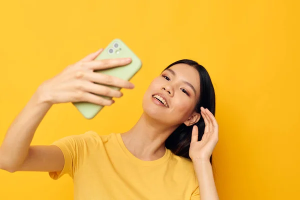 휴대 전화를 손에 들고 아시아의 모습을 한 여자가 셀카 스튜디오 모델을 그대로 만들고 있다 — 스톡 사진