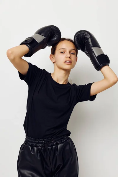 Hermosa chica en negro deportes uniforme guantes de boxeo posando fondo aislado — Foto de Stock