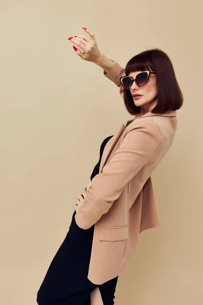 Foto mulher bonita em uma jaqueta bege estilo elegante óculos de sol luz fundo — Fotografia de Stock