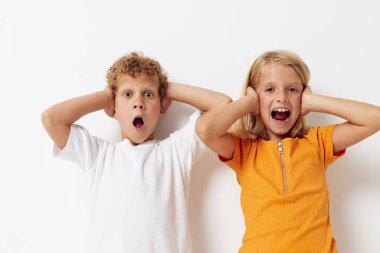 İki neşeli çocuk el hareketi yapıyor. Gülümse, rahat giyin, hafif arka plan.