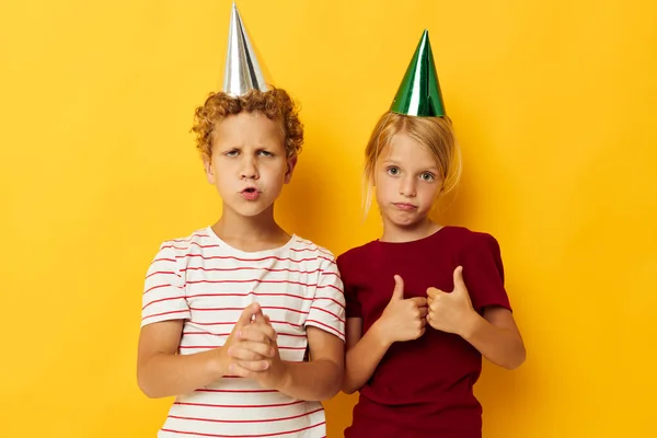 Lindo preescolar niños vacaciones diversión con gorras en su cabeza fondo amarillo —  Fotos de Stock