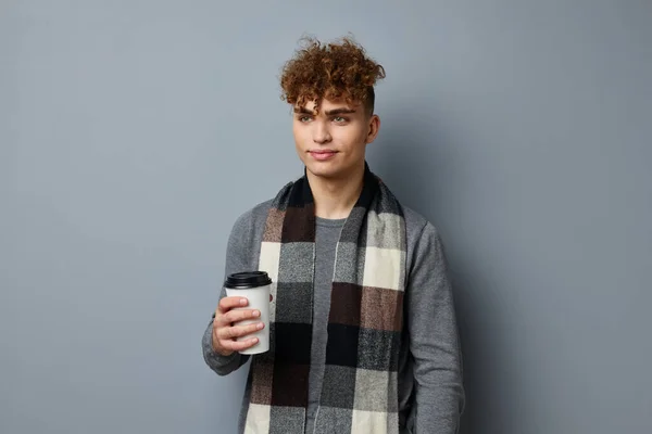 Pohledný mladý muž kostkovaný šátek pózování nápoj hrnek světlo pozadí — Stock fotografie