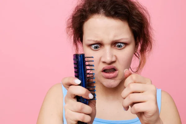 Young woman removes hair on a comb dissatisfaction isolated background unaltered — Stock Photo, Image