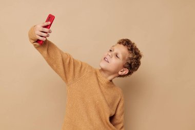 Kıvırcık saçlı, kırmızı telefon teknolojisi olan küçük bir çocuk.