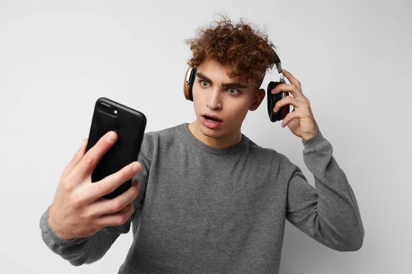 Дивний хлопець з телефоном в руці прослуховування музики на світлому фоні навушників — стокове фото