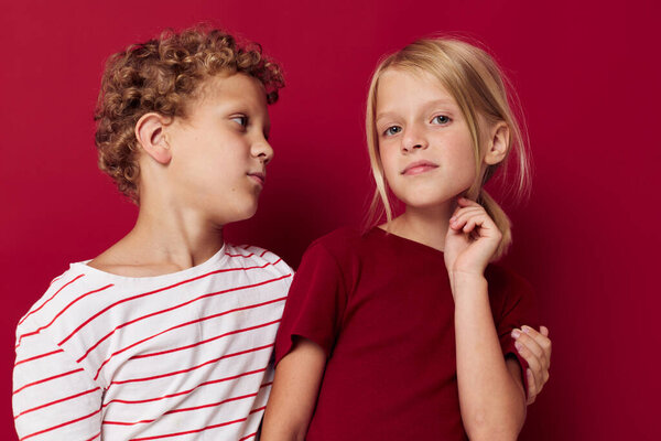 Portrait of cute children emotions stand side by side in everyday clothes red background