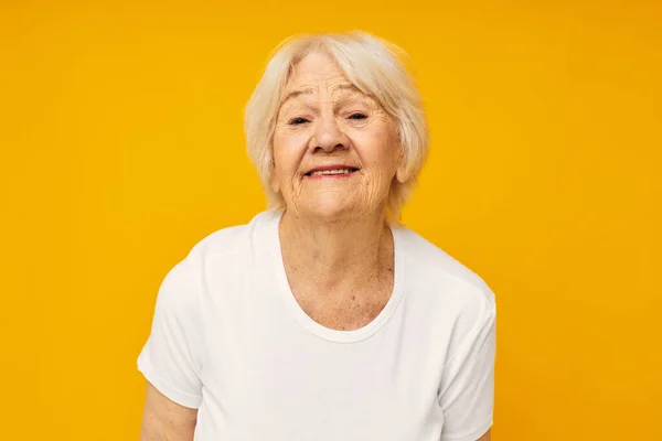 Foto de anciana jubilada en gestos casuales de camiseta con sus manos aisladas de fondo — Foto de Stock