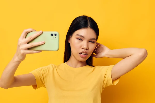 스마트폰을 손에 들고 있는 여성은 아무런 변화 없이 노란 배경을 클로즈업하며 즐거운 감정을 즐긴다 — 스톡 사진