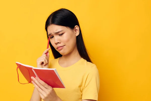 Charmante jeune femme asiatique dans un t-shirt jaune modèle de studio de formation carnet rouge inchangé — Photo