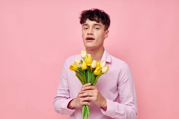 Портрет молодого чоловіка в рожевій сорочці з букетом квітів, що жестикулює своїми руками модель студії — стокове фото