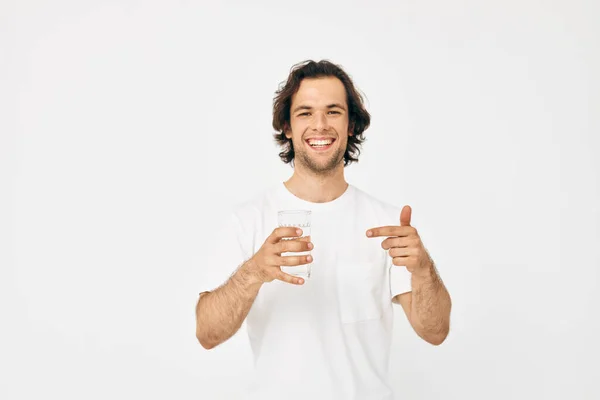 Ελκυστικός άνθρωπος σε ένα λευκό T-shirt ποτήρι νερό απομονωμένο φόντο — Φωτογραφία Αρχείου