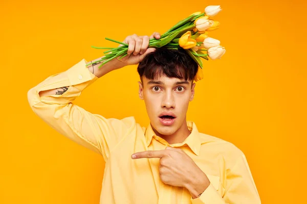아무런 변화 없이 노란 배경을 살려 주는 꽃다발을 든 낭만적 인 젊은 남자 친구의 사진 — 스톡 사진
