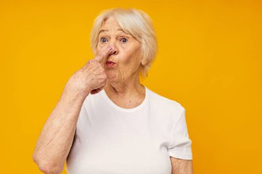 Beyaz tişörtlü emekli bir kadının, izole edilmiş, eğlenceli bir arka plan pozu.