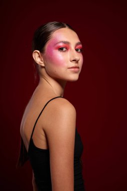 Güzel bir kadın parlak makyaj yapıyor. Moda cazibesi. Pembe arka plan değiştirilmemiş.