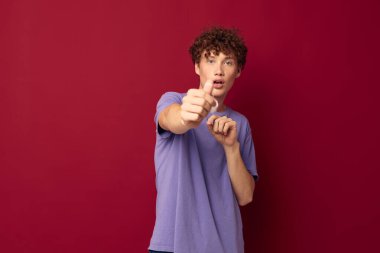 Mor tişörtlü genç bir adam. Tıbbi maske, el emniyetinde. Geçmişi değiştirilmemiş.