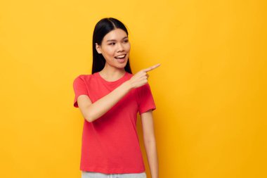 Çekici genç Asyalı kadın kırmızı tişörtleri modern stil stüdyo modelini değiştirmeden poz veriyor.