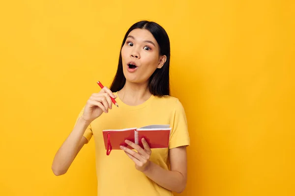 Jolie brune écrit dans un carnet avec un fond jaune crayon inchangé — Photo