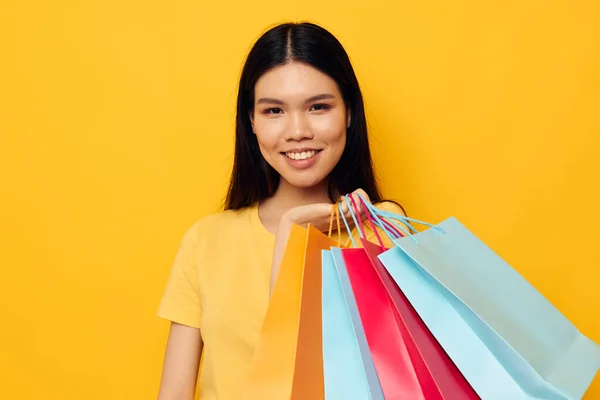 Portret aziatische mooie jonge vrouw met pakketten in handen winkelen geïsoleerde achtergrond ongewijzigd — Stockfoto
