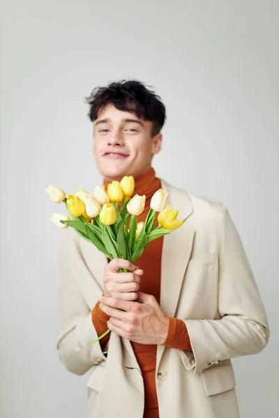 Photo young boyfriend in white jacket with a bouquet of yellow flowers elegant style Lifestyle unaltered — Fotografia de Stock