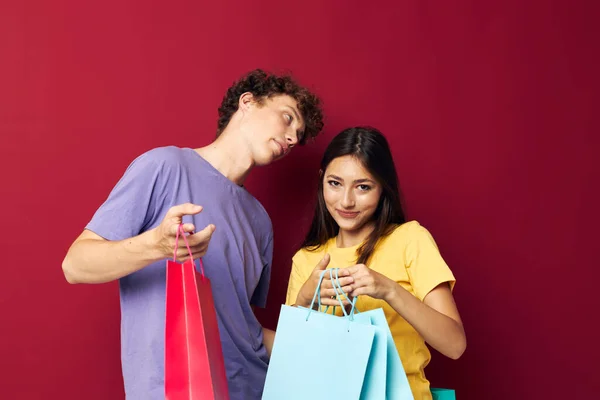 Tieners in kleurrijke T-shirts met tassen Shopping rode achtergrond ongewijzigd — Stockfoto