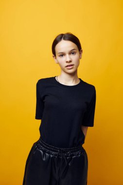 Siyah tişörtlü ve pantolonlu iyimser genç kadın izole edilmiş arka planda gülümsüyor.