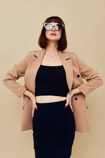 Piękna kobieta w beżowej kurtce elegancki styl okulary przeciwsłoneczne lekkie tło — Zdjęcie stockowe