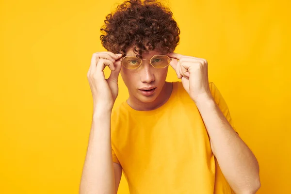 젊고 곱슬곱슬 한 청년 스타일의 안경 녹음실에 아무런 변화 없이 노란 배경 옷을 입고 있는 모습 — 스톡 사진