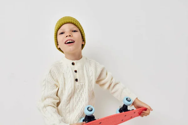 Bambina in cappelli con uno skateboard tra le mani sfondo chiaro — Foto Stock