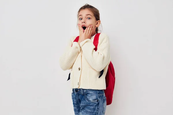 Hezká mladá školačka s červeným batohem představuje izolované pozadí — Stock fotografie