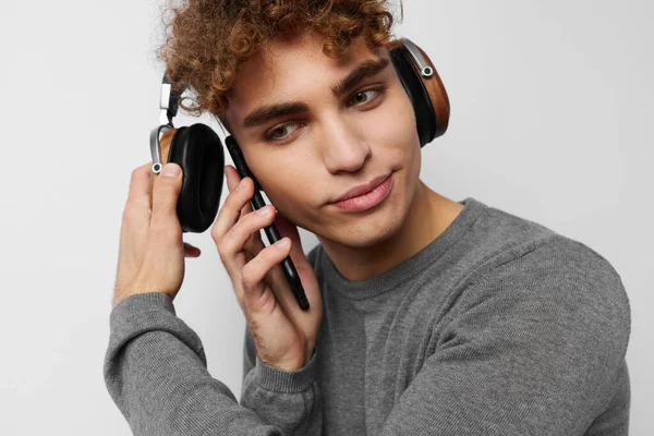 Handsome young man in a gray sweater headphones fashion light background — Stock Photo, Image